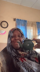 Woman enjoys tea from green teapot in Madangala home