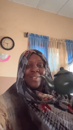 Woman enjoys tea from green teapot in Madangala home