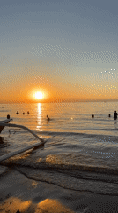 Golden sunset scenes captured along Bali coast with swimmers, boats