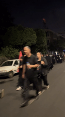 Nighttime street scene in Tehran, people walking along tree-lined road