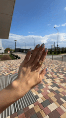 Person displays jewelry and nail art in urban setting