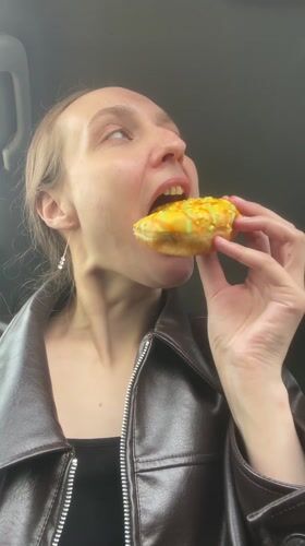 Woman enjoys decorated donut in car in Sharkan