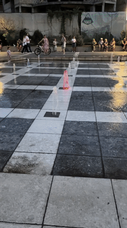 Chișinău plaza fountain lights up at dusk as people play