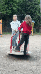 Children play on park roundabout near illuminated riverside recreation area