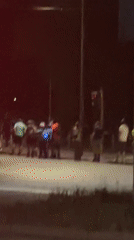 Dozen people gather, converse at Milan intersection at night