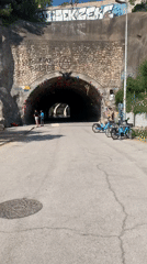Two pedestrians walk past decorated tunnel entrance in Barcelona