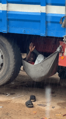 Hammock rigged under a truck chassis during rain in Ajara
