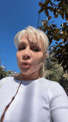 Woman in white cardigan spotted outdoors among palm trees