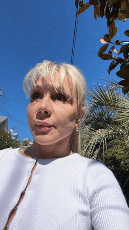 Woman in white cardigan spotted outdoors among palm trees