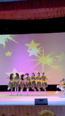 Young girls perform dance routines on stage before audience