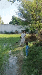 Man and boy play near water in rural field