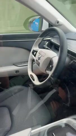 The video shows the dashboard and windshield view from inside a car. The steering wheel is white and grey, and the seats are dark grey.  A dashcam is mounted near the top of the windshield. Two tablets are attached to the windshield and display navigation, including estimated time of arrival.  A black car can be seen driving on the road ahead.
