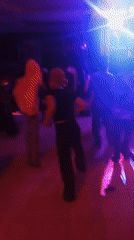 People dance at nightclub with colorful lights early morning