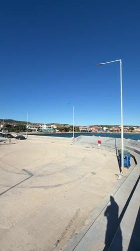 People gather at sunny Greek harbor on spring afternoon