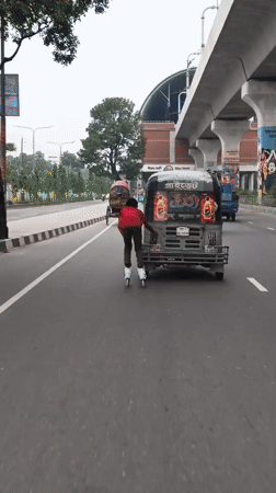 Person roller skates behind auto-rickshaw on busy Dhaka street
