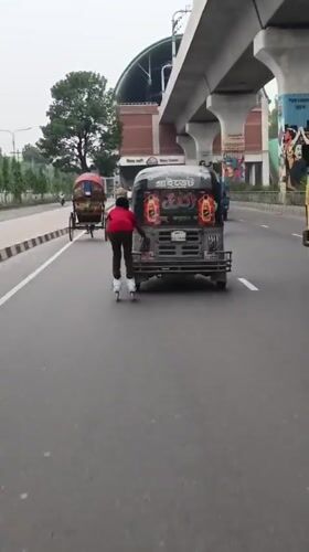 Person roller skates behind auto-rickshaw on busy Dhaka street