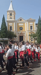 Barefoot procession in white and red approaches decorated Málaga church
