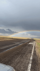 Double rainbow appears over wet rural Russian road
