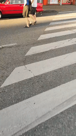 Pedestrians crossing a Batumi street, red BMW parked nearby