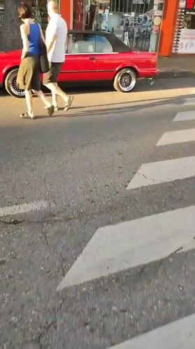 Pedestrians crossing a Batumi street, red BMW parked nearby