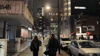 Four pedestrians walk wet Montreal street at night