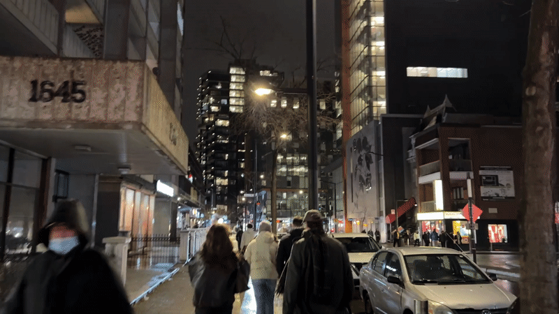 Four pedestrians walk wet Montreal street at night