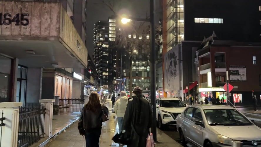 Four pedestrians walk wet Montreal street at night