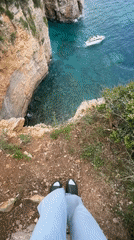 Tourist photographs scenic Sveti Stefan coastline from cliff overlook