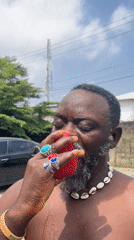 Eating red fruit outdoors in Ado, Nigeria