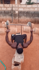 Man exercises with homemade weights in rural Bukuru, Nigeria