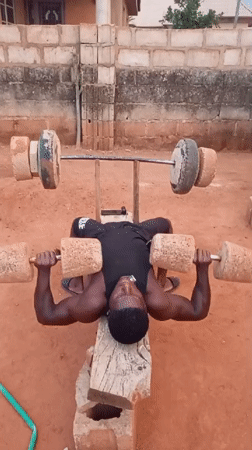 Man exercises with homemade weights in rural Bukuru, Nigeria