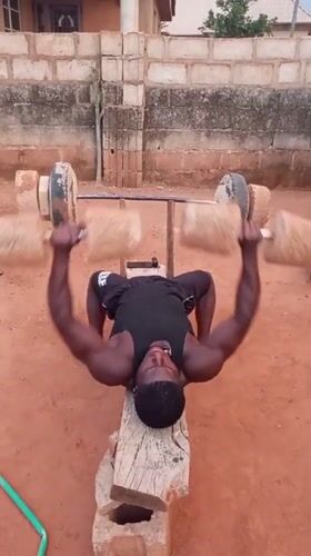 Man exercises with homemade weights in rural Bukuru, Nigeria