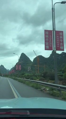 Car drives past red banners, sculpture in Guilin hills