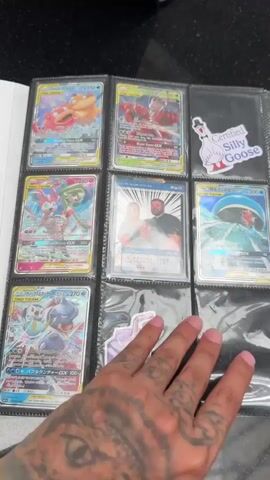 A hand is seen flipping through a binder filled with Pokemon cards. The binder pages are clear plastic sleeves, each holding multiple cards. The cards are of various Pokemon characters and designs, some appearing to be rare or holographic. The background is dark and appears to be a countertop. The video is shot from a close-up perspective, focusing on the cards and the hand interacting with them.
