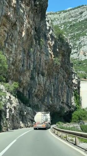 Tank truck travels highway near cliff face in Montenegro