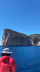 Tourist observes cliff island from boat near Alghero