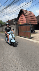 Woman rides blue scooter through North Kuta early morning