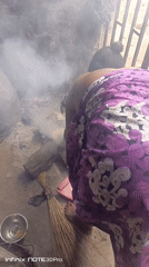 Person tends outdoor cooking fire in traditional dress