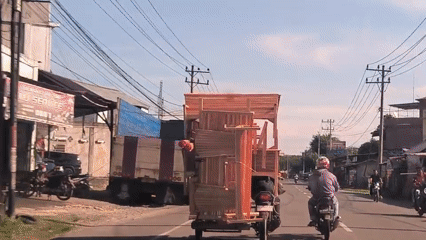 Motorcycle carries oversized furniture load on Indonesian street