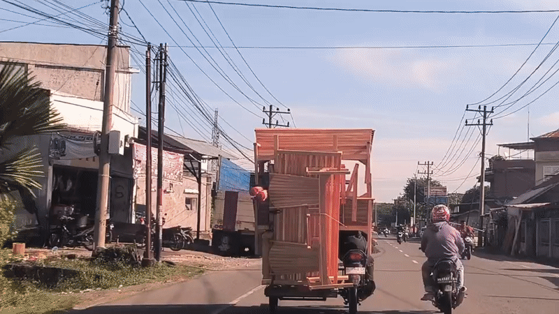 Motorcycle carries oversized furniture load on Indonesian street
