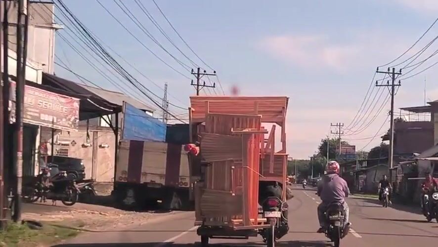 Motorcycle carries oversized furniture load on Indonesian street