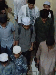 Young men in traditional Muslim dress walk down stairs in Lhokseumawe