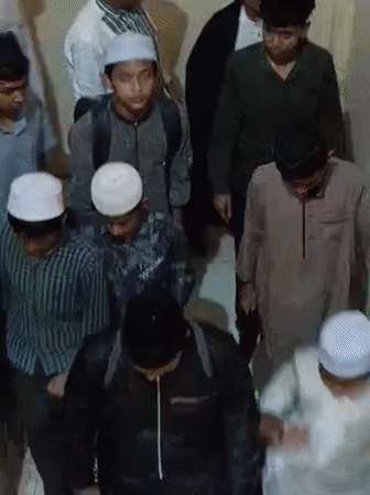Young men in traditional Muslim dress walk down stairs in Lhokseumawe
