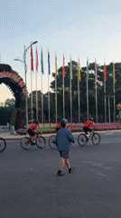 Cyclists in red ride through flower archway in Da Lat
