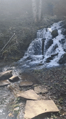 Hiker captures waterfall and trail markers near mountain paths
