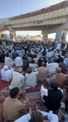 Outdoor prayer gathering on red carpets beneath Quetta overpass