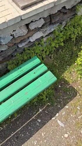 Person filmed standing on gravel path near green bench