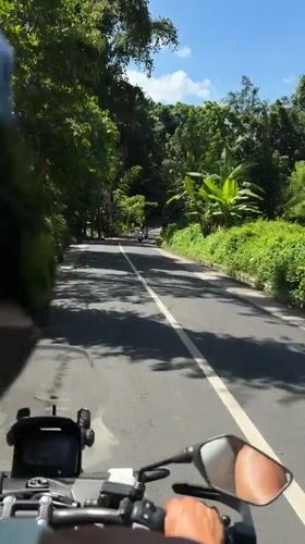 Motorcyclist rides through green countryside in Kediri, Indonesia
