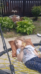 Girl plays in backyard swing while cat rests nearby
