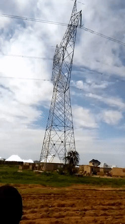 Leaning power tower and people on foot in affected area